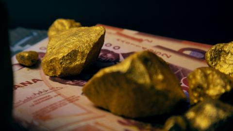 Ghanaian cedi notes and lump of Gold on dark background
