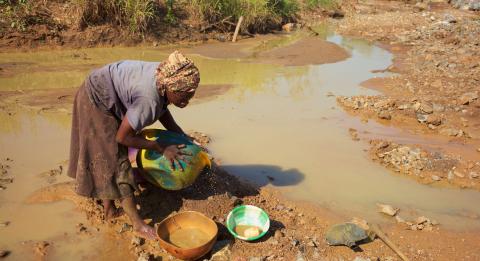 A Dioula woman searching gold in a river rich in alluvial gold in Côte d'Ivoire.