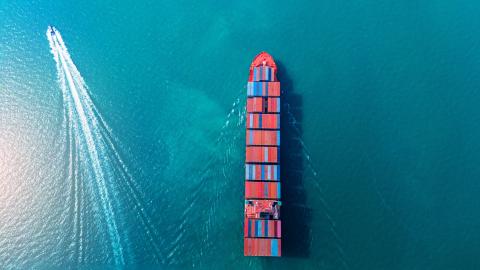 large container ship and fast boat in the blue ocean. Global trade logistics, cargo transport, energy crisis from war, and Strait of Hormuz blockade concept.